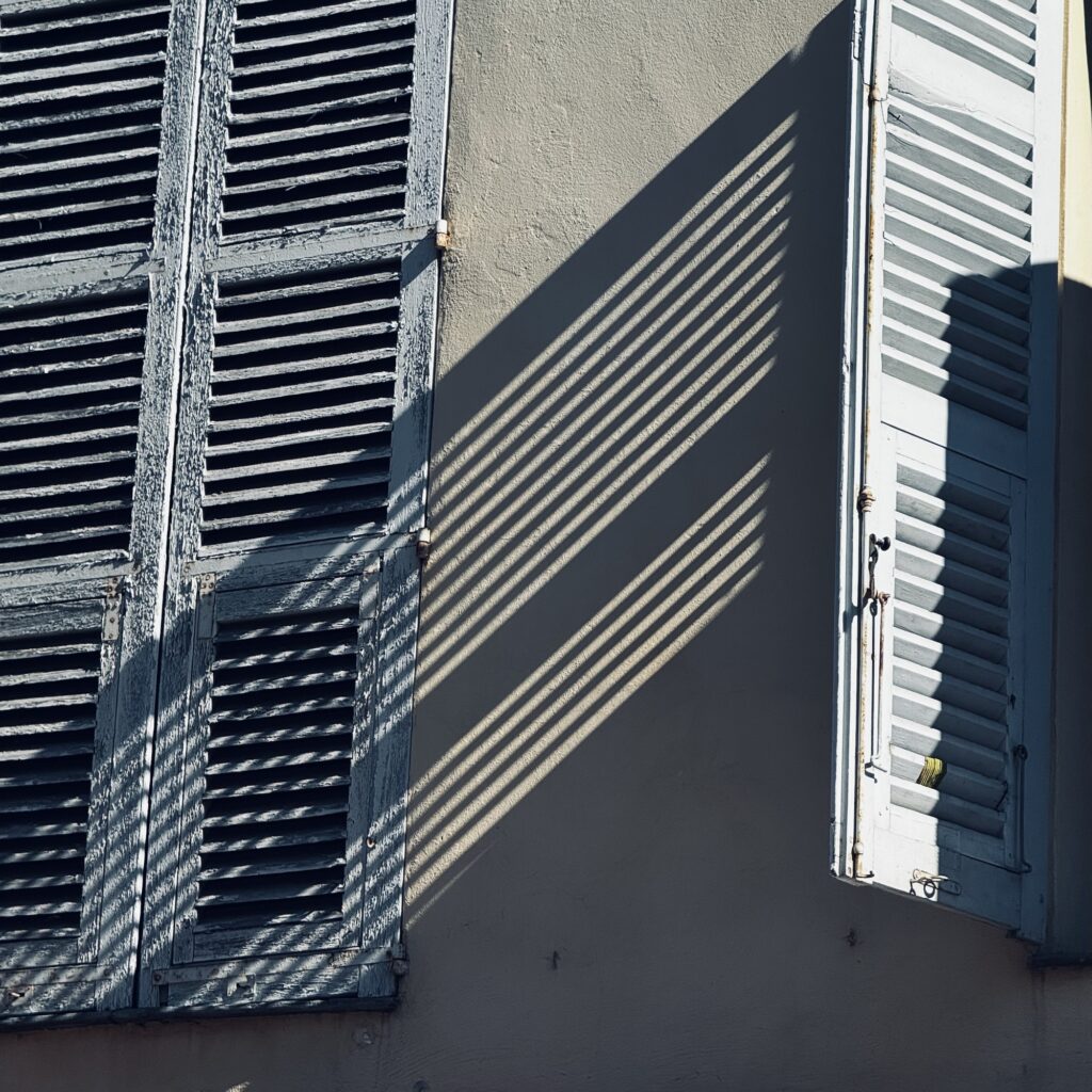 A shutter throws a shadow across a wall on a building in Antibes in the South of France