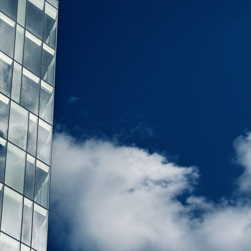 The edge of a glass building to the left gives way to blue sky and wispy clouds in the background